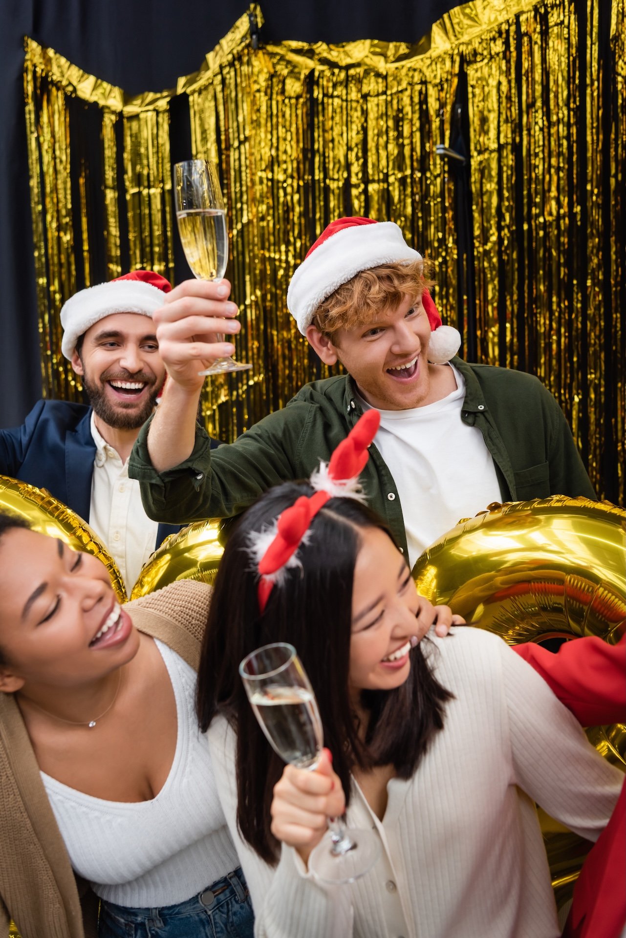 Groupe d'amis célébrant Noël avec chapeaux de Père Noël et champagne.